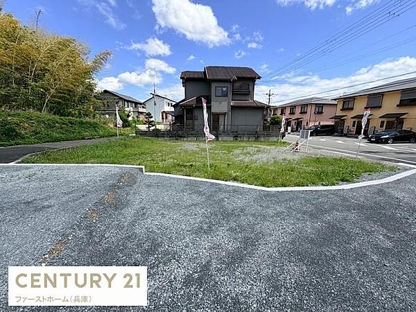 角地に位置する現地土地写真です。周囲は整った住宅街で陽当たりも良好です。前面道路は広くて車の出入りもスムーズにできます。近隣には緑も多く落ち着いた雰囲気が広がります。