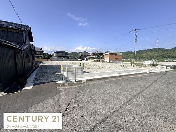 広々とした現地土地写真です。前面道路が整っておりアクセスしやすい立地となっています。明るい日差しが差し込み周辺には住宅が並び落ち着いた雰囲気が感じられます。