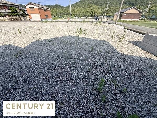 開放的な現地土地写真です。周囲には住宅や自然が広がり落ち着いた環境が感じられます。敷地内は整地されており自由な設計が検討できます。前面道路も広く車の出入りもスムーズです。