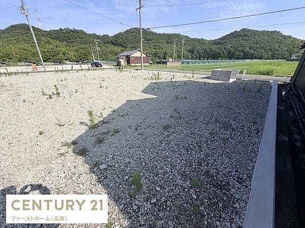 広々とした敷地が特徴の現地土地写真です。平坦で整備された地面が印象的で周囲には自然が広がっています。道路に面しておりアクセスも良好です。周辺は静かな環境となっています。
