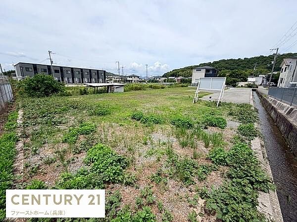 現地土地写真から広々とした敷地の様子が伝わります。周囲に建物があり整然とした街並みが印象的です。開放感があり様々な活用が期待できます。前面道路も確認できアクセスしやすい立地です。