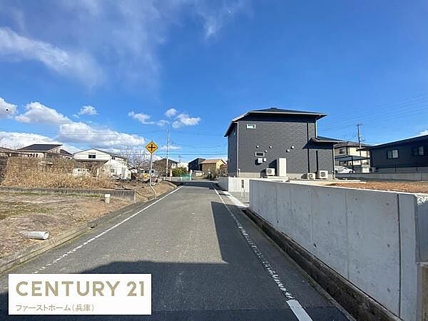 前面道路が広く開放感のある現地の写真です。車の出入りがしやすい直線道路となっています。周辺は住宅が立ち並び落ち着いた雰囲気となっています。舗装された道路が生活の利便性を高めます。