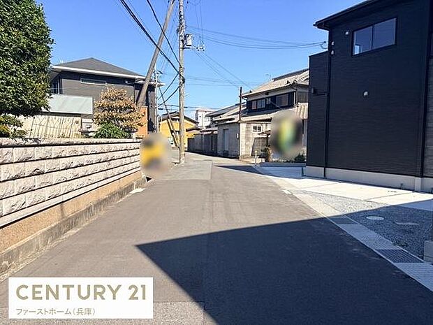 前面道路は舗装されており車の出入りもしやすい幅があります。周囲には住宅が並び落ち着いた雰囲気の街並みです。電柱や配線も整然と設置されています。周辺の建物も手入れが行き届いています。