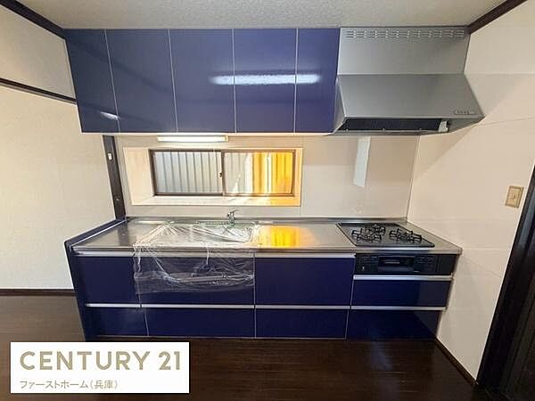 落ち着いた色合いのキッチンが目を引きます。窓付きで自然光が入りやすく換気もしやすい設計です。使い勝手の良いシンクとコンロが配置され収納スペースも豊富です。清潔感のある仕上がりとなっています。
