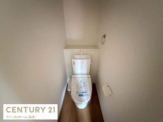 シンプルですっきりとしたデザインのトイレです。壁面に収納スペースがあり使いやすさに配慮されています。明るい色合いの内装で清潔感があります。床材も落ち着いた色調です。