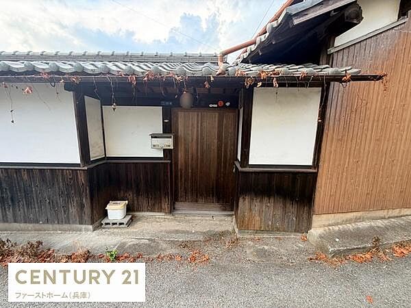 木材と白壁の組み合わせが印象的な玄関です。落ち着いた色合いが外観に調和しています。郵便受けや照明も備わっており実用的です。日本家屋らしい雰囲気を感じられます。玄関前にはちょっとしたスペースがあります。