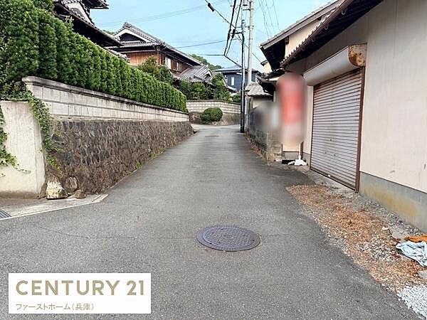 前面道路がしっかり舗装されており周囲には落ち着いた住宅が並んでいます。道幅もあり車の通行がスムーズです。静かな住環境が感じられる現地の様子です。周辺には緑が見られ街並みに調和しています。