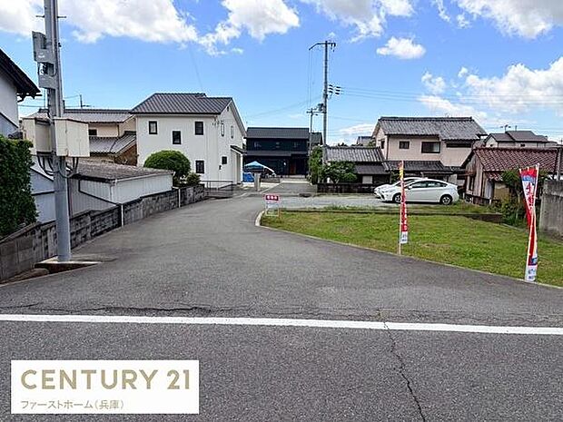 前面道路を含む現地の様子がしっかりと確認できます。現地周辺は落ち着いた環境で道路幅も確保されています。近隣は住宅が整然と並び静かな雰囲気です。駐車スペースもゆとりを感じられる現地写真です。