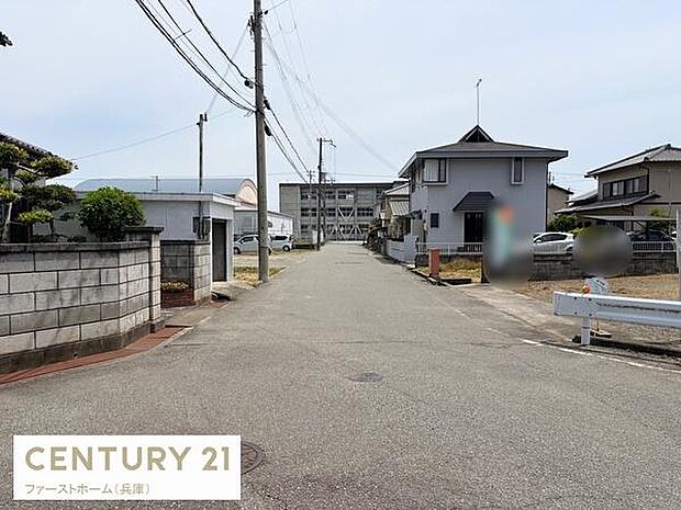前面道路が見通しの良い直線で周辺の建物や住宅が落ち着いた雰囲気を作っています。電柱や配線も整然としていてゆとりを感じられます。舗装された広めの道路は移動や車の出し入れにも便利です。