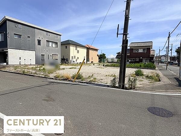 現地写真では前面道路の幅員がしっかりと確保されていることが確認できます。周辺には住宅が立ち並び道路の舗装も整っています。電柱や電線も比較的整然と配置されています。