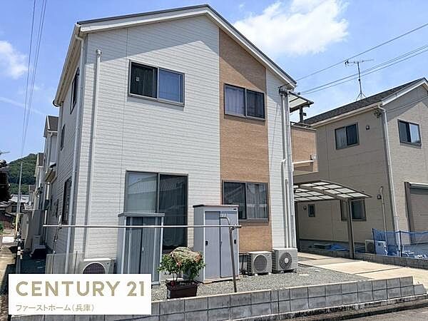 シンプルな色合いとすっきりとした外観が印象的です。広々とした敷地で駐車スペースも確保されています。窓が多く明るい雰囲気です。エアコンの室外機が設置されています。家庭菜園なども楽しめます。
