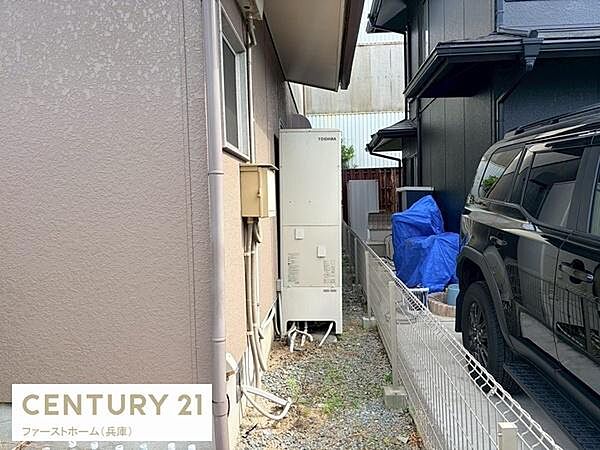 屋外には設備が設置されており手入れがしやすい空間です。フェンスでしっかりと仕切られているため安心感があります。住宅の側面スペースが確保されており換気やメンテナンスにも適しています。
