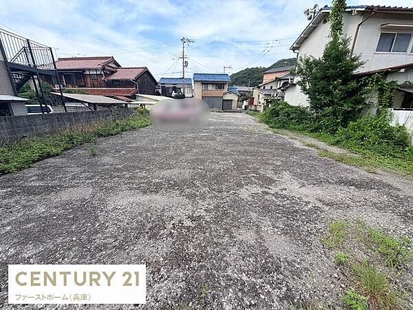 広々とした敷地が特徴的な土地の写真です。周囲には住宅が建ち並び町の雰囲気が感じられます。前面道路へのアクセスも可能です。用途に応じた活用が期待できます。開放的な空間が印象的です。