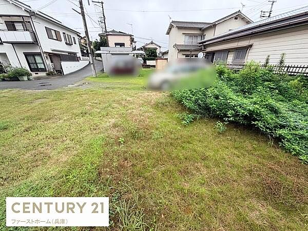 現地土地写真から広々とした敷地が確認できます。周辺には住宅が並んでおり静かな街並みが感じられます。道路に面したアクセスの良さも魅力です。敷地内には緑が広がっており使い方の幅が期待できます。