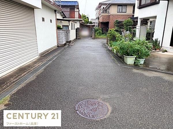 前面道路は舗装されており周囲に住宅が立ち並ぶ落ち着いた環境です。道路幅も車の通行が可能な広さとなっています。道沿いには植栽やプランターが設置され手入れが行き届いています。
