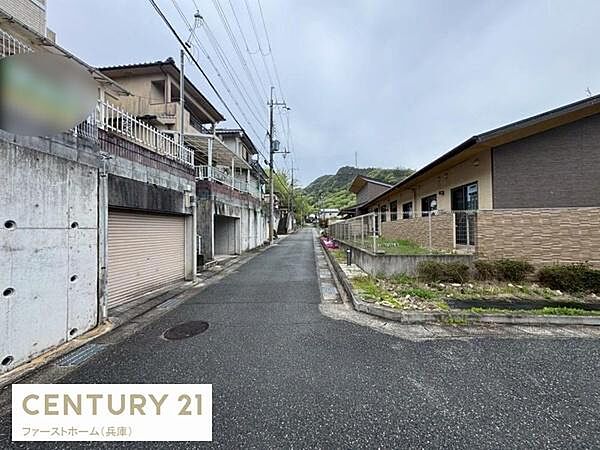 現地写真では周辺の住宅や建物が並ぶ落ち着いた雰囲気の道路がご覧いただけます。前面道路は見通しも良く静かなエリアの様子が伺えます。道路幅も十分に確保されており歩行や車両の通行もしやすい印象です。