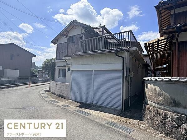 道路に面した角地の建物です。シャッター付きのガレージが備わっています。バルコニーが付いているためスペース活用も可能です。周囲は落ち着いた住環境が感じられます。昔ながらの趣のある外観が特徴です。