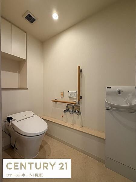 シンプルで清潔感のある内装のトイレです。収納スペースも備わっており使いやすさに配慮されています。手すりも設置されていて安心してご利用いただけます。照明も明るく快適な空間です。