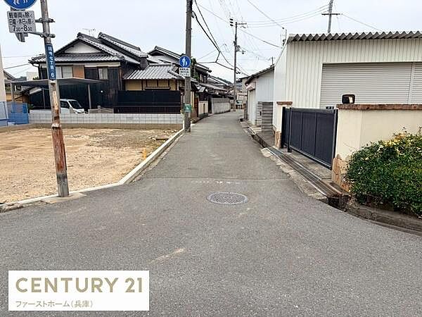 現地前面道路は整った舗装で歩行や車両の通行がしやすい状態です。周辺には落ち着いた住宅が並び閑静な雰囲気が感じられます。電柱や標識も視認しやすい位置に配置されています。