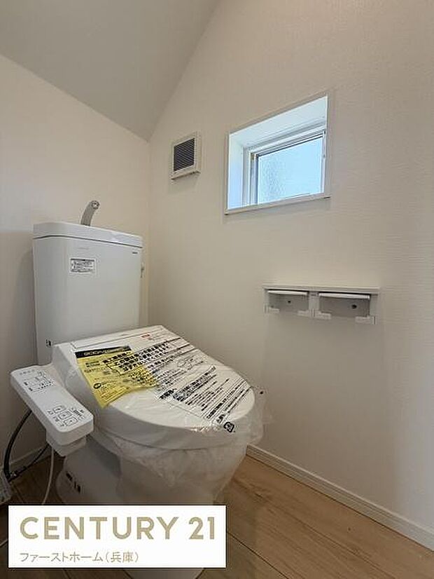 清潔感のあるトイレ空間です。小窓が設けられており自然光が心地よく入ります。壁付けの換気設備も備わっています。温水洗浄便座が設置されています。ペーパーホルダーは2連タイプです。