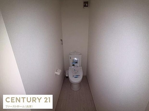清潔感のあるシンプルなトイレ空間です。壁紙と床材の色合いが統一され落ち着いた印象です。収納スペースや換気口が設けられています。ペーパーホルダーも設置済みです。