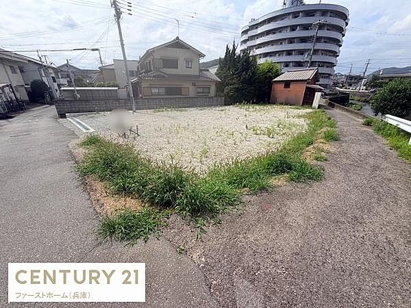 周囲には住宅やマンションが立ち並ぶエリアの現地土地写真です。道路に面しておりアクセスもスムーズです。平坦な形状で活用しやすい土地です。落ち着いた住宅街の雰囲気が特徴的です。