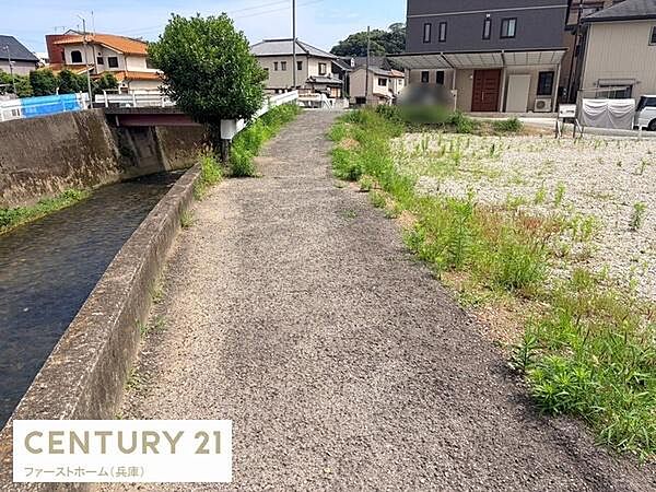 川沿いの道が隣接しており開放感のある風景が広がっています。周辺には住居が立ち並び落ち着いた雰囲気のエリアです。道幅も確保されており移動もスムーズです。