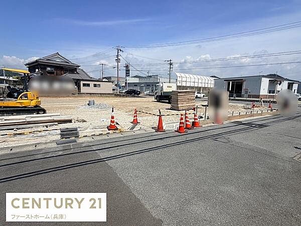 周辺は住宅や建物が点在し落ち着いた雰囲気が感じられる現地土地写真です。整地や重機も見られ今後の利用や建築も検討しやすい状況となっています。道路に面しておりアクセスにも配慮されています。
