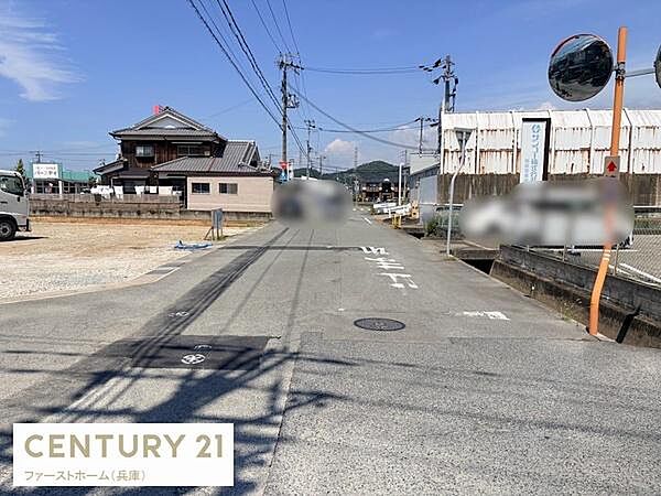 前面道路は幅員がしっかりと確保されており車両の通行もスムーズです。周辺は落ち着いた環境で見通しも良好です。電柱や標識なども整備され安全性に配慮された道路です。周囲の建物との調和が取れた現地写真です。
