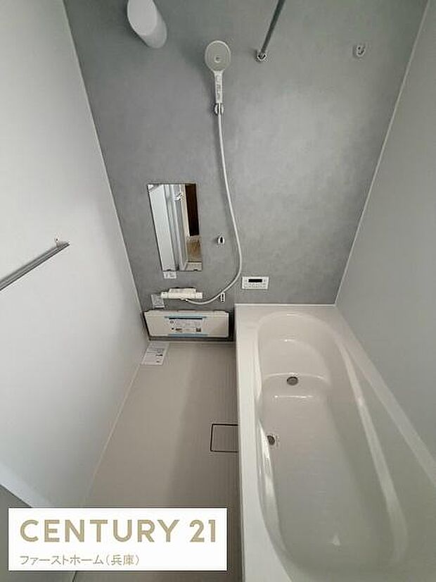 浴室全体が清潔感ある印象です。シンプルなデザインで手入れもしやすそうです。壁面の落ち着いたカラーが空間を引き締めています。鏡や棚も設置されていて便利です。浴槽もゆったりとした造りです。
