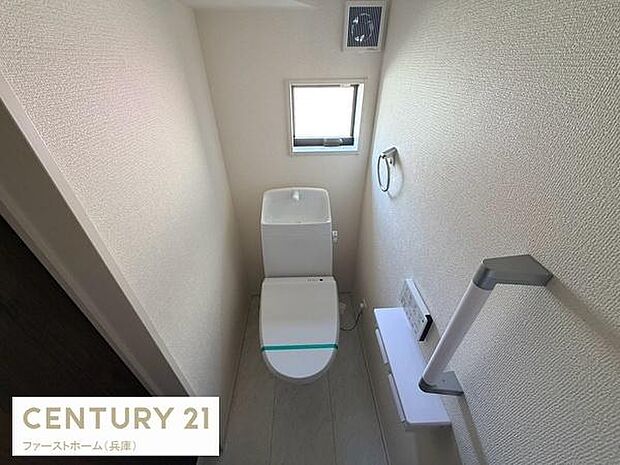 トイレには小窓が設けられており自然光が差し込みます。手すり付きで安心してご利用いただけます。シンプルなデザインで清潔感が感じられる空間です。ペーパーホルダーやタオル掛けも設置されています。