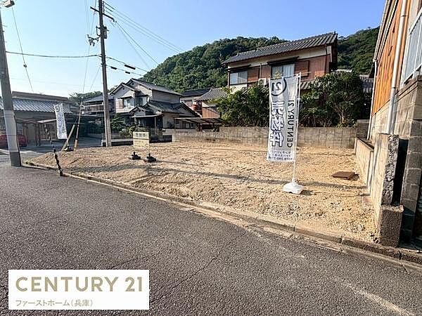 現地土地写真です。敷地は道路に面しており日当たりも良好な印象です。周囲には自然豊かな環境が広がり開放感があります。前面道路も幅があり車の出入りがしやすそうです。