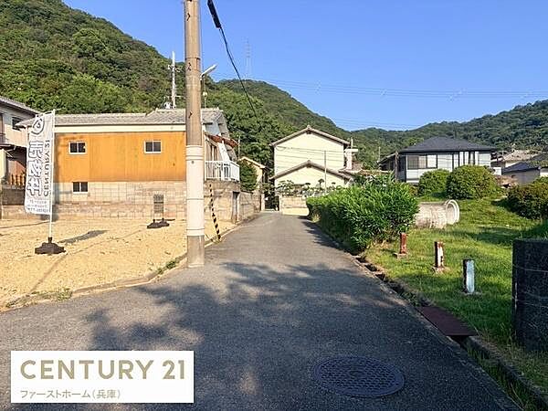 周辺には自然が広がり穏やかな住環境が感じられる現地写真です。前面道路は車の通行も安心な幅で確保されています。敷地が見渡しやすく建築計画も立てやすい点が魅力です。