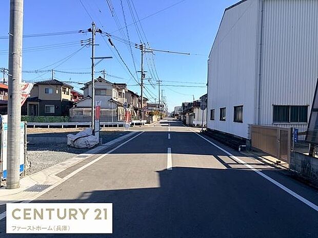 道路幅がしっかりと確保されているため車の通行も安心です。周囲には住宅や工場が建ち並び街並みが整っています。前面道路が舗装されておりすっきりとした印象の現地写真です。