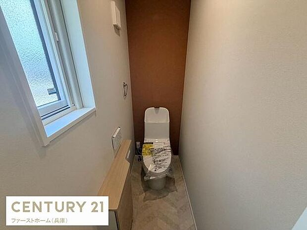 落ち着いた色合いの壁が特徴的なトイレです。小窓が設けられており明るさが感じられます。空間がすっきりとしており清潔感のある印象です。設備も新しく快適にお使いいただけます。