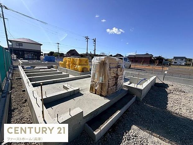 青空が広がる開放的な敷地で基礎工事が進行中です。ゆとりある区画で道路へのアクセスも良好です。周囲に住宅が立ち並ぶ落ち着いた環境となっています。