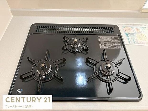 三口コンロが設置されており同時に複数の料理が可能です。天板がフラットで掃除もしやすい仕様です。シンプルで使いやすいキッチン設備となっています。キッチン周りもすっきりとした印象です。