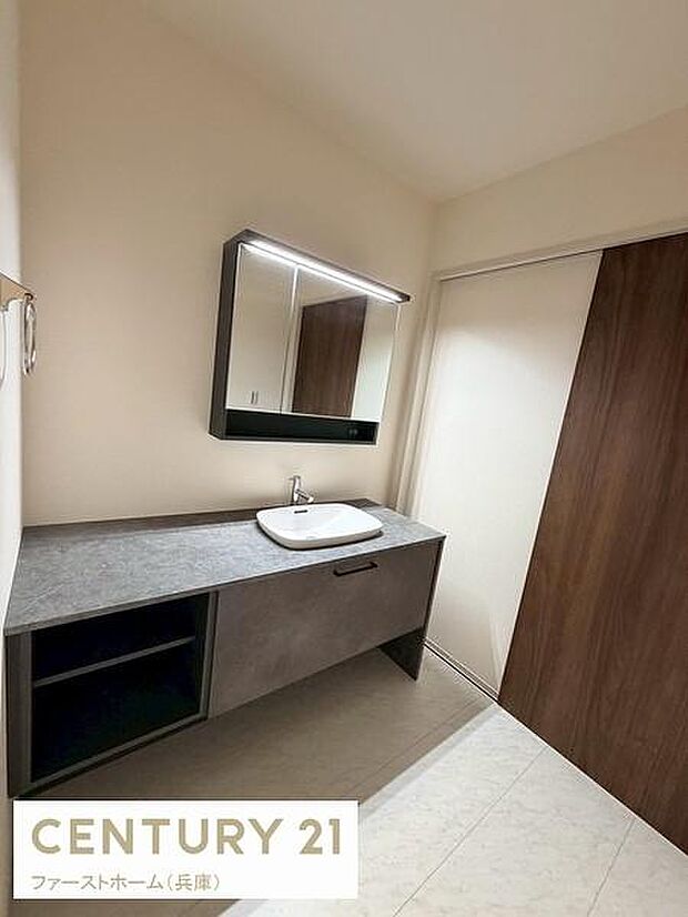 シンプルなデザインの洗面所で空間が広く感じられます。鏡付きのキャビネットが備わっており収納スペースも便利です。落ち着いた色合いのカウンターが特徴的です。スッキリとした印象の内装です。