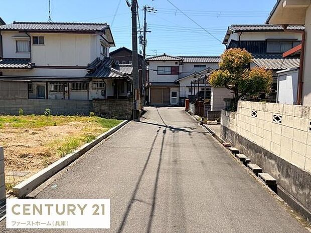 現地の前面道路は舗装されており落ち着いた雰囲気が感じられます。建物の外観や周囲の住宅も確認でき周辺の様子も一目でわかります。