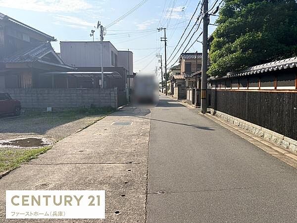周辺は落ち着いた雰囲気の住宅地です。舗装された前面道路は車の通行にも便利です。両側に建物が並び安心感のある環境です。電柱や配線も整然と配置されています。道路幅も確保されており通行しやすい立地です。