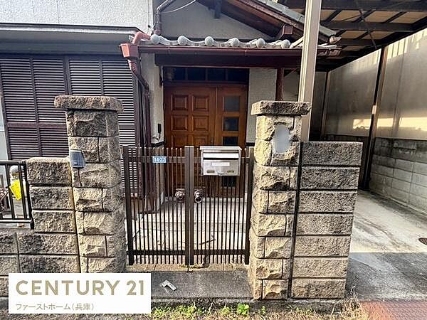 重厚感のある門柱と鉄製の門扉が印象的な玄関です。木製ドアが落ち着いた雰囲気を演出しています。郵便受けや表札スペースも備わっており機能性も感じられます。