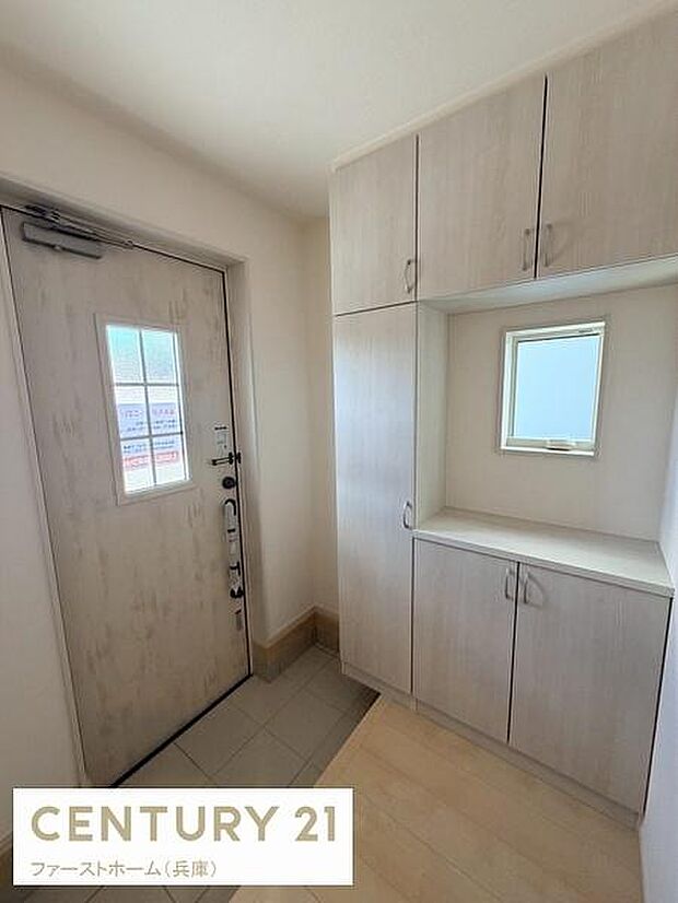 玄関には収納スペースがしっかりと設けられており整理整頓しやすい空間です。窓からの自然光が入るため明るさも感じられます。落ち着いた色合いのデザインで全体的に清潔感があります。