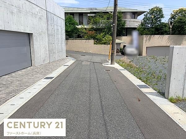 前面道路が広く車の出入りもスムーズに行えます。周囲は閑静な環境で落ち着いた雰囲気が感じられます。道路沿いの美しいコンクリート外壁が印象的です。建物と道路の接道状況もしっかりと確認できます。