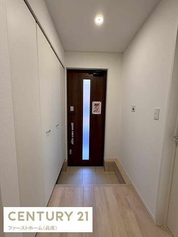 玄関ドアには縦長のスリット窓があり自然光を取り入れ明るい印象です。シンプルな白い収納が壁面に設置されているためすっきりした空間を感じられます。