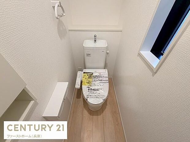 シンプルなデザインのトイレで清潔感が感じられます。窓付きで換気にも配慮されています。床材と壁紙の色合いが調和した空間です。ペーパーホルダーなどの備品も備え付けられています。機能的で扱いやすい形状です。