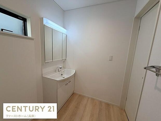 明るい色合いのフローリングが特徴的な洗面台です。三面鏡で使いやすさが魅力となっています。収納スペースも設けられており整理整頓がしやすい印象です。照明付きの鏡で毎日の身支度も快適に行えます。