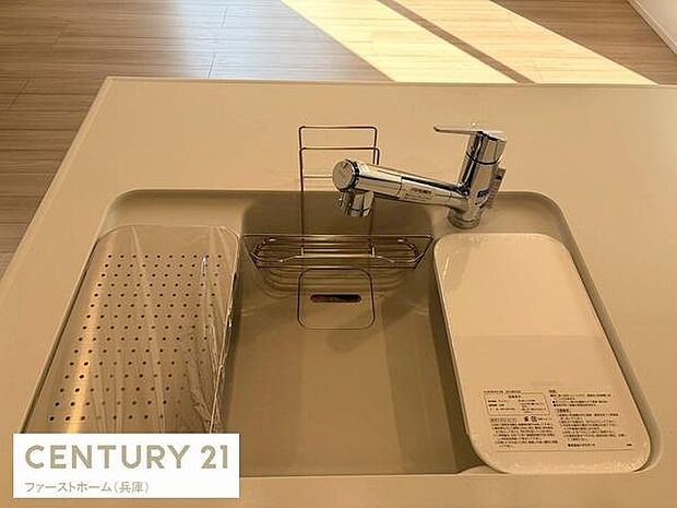 シンプルで洗練されたデザインのキッチンシンクです。水栓が使いやすく作業スペースも確保されています。付属のプレートや水切りも便利に活用できます。明るい色調で清潔感のある印象です。