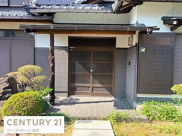 趣のある和風デザインが特徴的な玄関です。広々としたアプローチで開放感があります。落ち着いた色合いの外壁が周囲の緑と調和しています。引き戸タイプで出入りがしやすい点も魅力です。