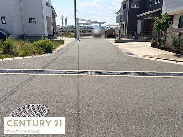 前面道路が広く車の出入りがしやすい現地写真です。周囲に住宅が整然と並びきれいな街並みが特徴的です。道路の舗装も良好で日当たりのよい開放的な印象を受けます。