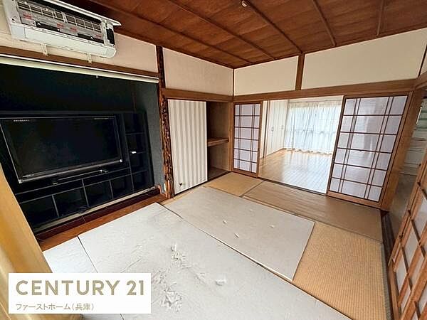 障子と畳の組み合わせが特長の和室です。収納スペースやテレビ台も設置されており利便性が感じられます。続き間があるため空間が広く感じられます。天井や壁の木材が重厚感を演出しています。